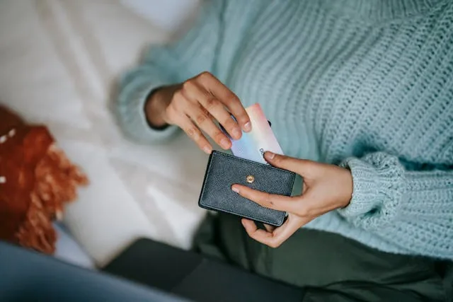 Person pulling a card out of a black wallet